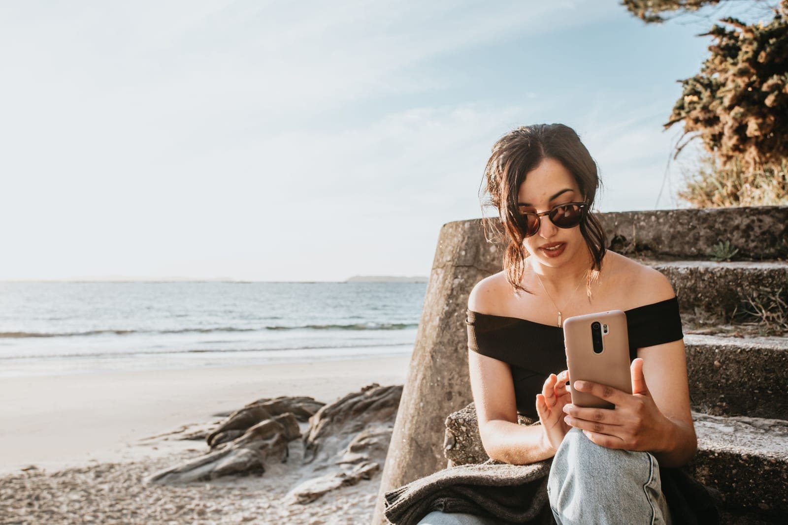 A woman in sunglasses relaxing on a bright, sunlit beach