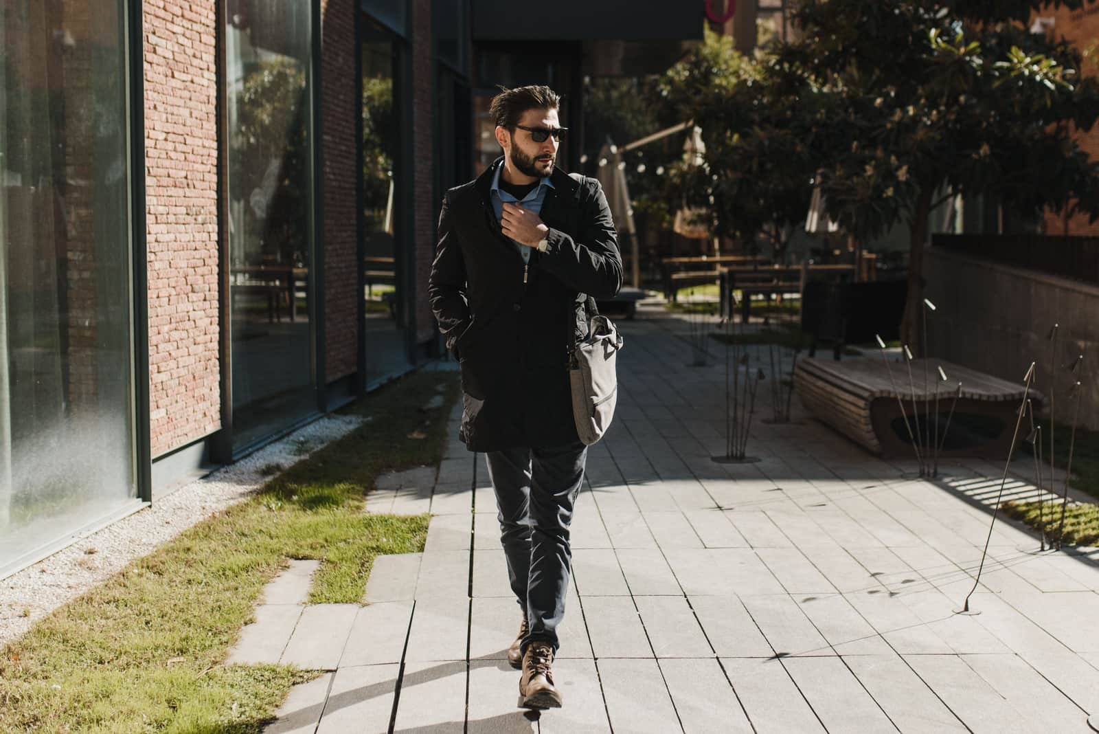 A person walking a sunny city street wearing classic sunglasses